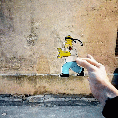 A Person Is Holding A Paper Cut Out Of Homer Simpson In Front Of A Wall That Says Efly GIF