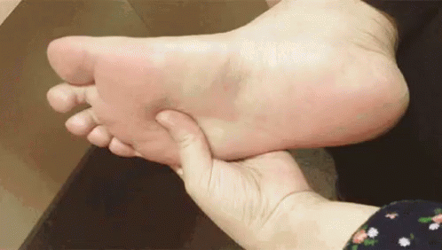 A Person Is Holding A Person 'S Foot In Their Hands . GIF
