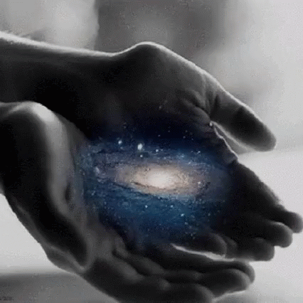 A Person Is Holding A Picture Of The Galaxy In Their Hands . GIF
