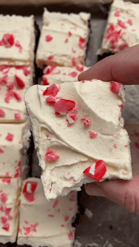 A Person Is Holding A Piece Of Cake With Candy Canes On Top GIF