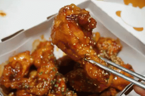 A Person Is Holding A Piece Of Chicken With Chopsticks GIF