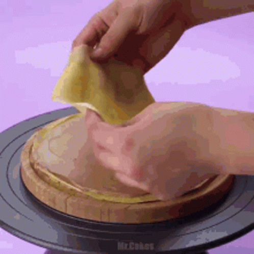A Person Is Holding A Piece Of Food On Top Of A Wooden Board . GIF