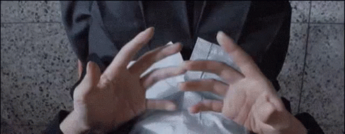 A Person Is Holding A Piece Of Paper Between Their Hands . GIF