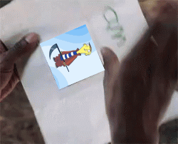 A Person Is Holding A Piece Of Paper That Has A Picture Of A Cartoon Character On It GIF