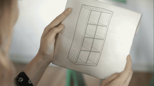 a person is holding a piece of paper with a drawing of a shelf