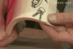 A Person Is Holding A Piece Of Paper With A Drawing Of Keys And A Watch On It GIF