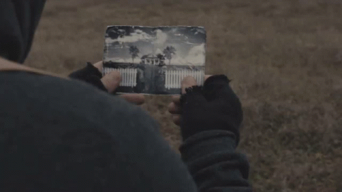 a person is holding a piece of paper with a picture of a house on it