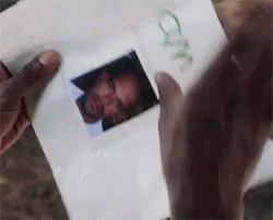 A Person Is Holding A Piece Of Paper With A Picture Of A Man 'S Face On It GIF