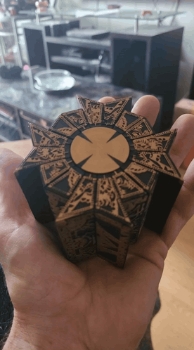 a person is holding a piece of wood with a cross in the center