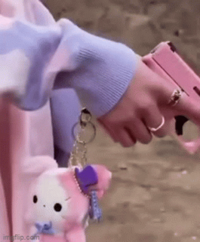 A Person Is Holding A Pink Gun In Their Hand While Wearing A Ring . GIF