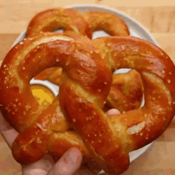 A Person Is Holding A Pretzel In Their Hand . GIF