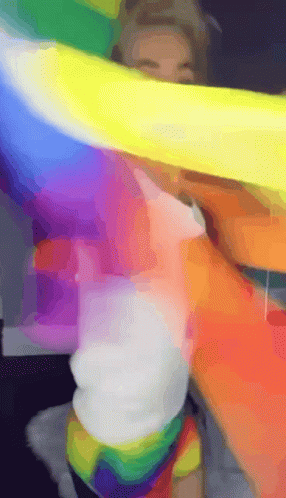 A Person Is Holding A Rainbow Flag Over Their Head GIF