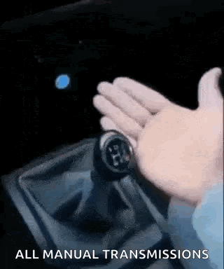 A Person Is Holding A Shifter In A Car And Pressing A Button . GIF