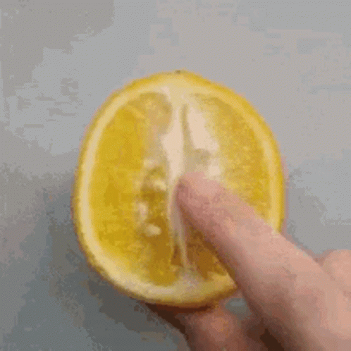 A Person Is Holding A Slice Of Lemon With Their Finger On It GIF
