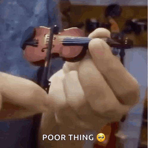 A Person Is Holding A Small Violin In Their Hand With The Caption Poor Thing . GIF