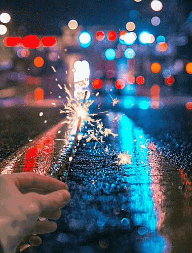 A Person Is Holding A Sparkler In Front Of A Blurry Background GIF