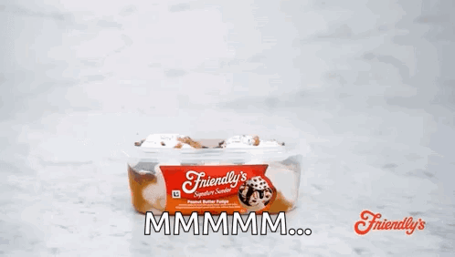 A Person Is Holding A Spoon Over A Container Of Friendly 'S Peanut Butter Fudge . GIF