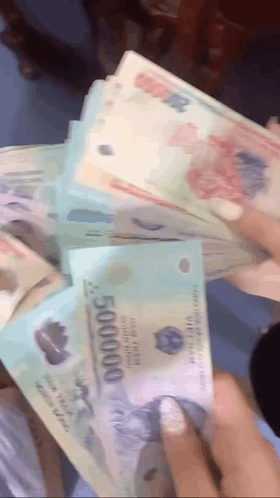 A Person Is Holding A Stack Of Money That Says 500000 On It GIF