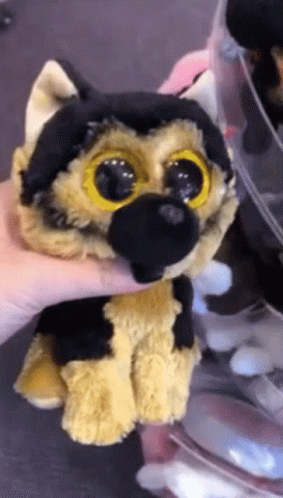 A Person Is Holding A Stuffed Animal That Looks Like A German Shepard GIF