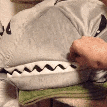 A Person Is Holding A Stuffed Animal That Looks Like A Shark . GIF