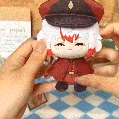 A Person Is Holding A Stuffed Doll Wearing A Hat And A Red Coat GIF