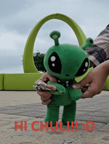 a person is holding a stuffed green alien with the words hi chuli !!! d written on the bottom