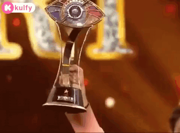 A Person Is Holding A Trophy In Their Hand In Front Of A Stage . GIF