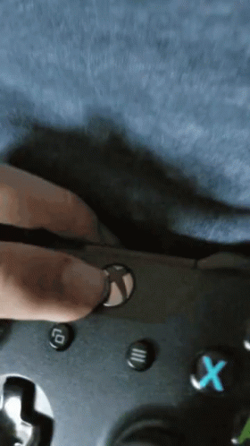 A Person Is Holding A Video Game Controller With A Blue X Button On It GIF