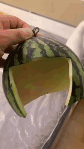 A Person Is Holding A Watermelon With A Hole In It GIF