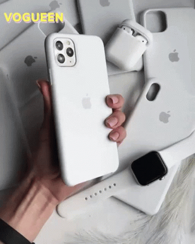 A Person Is Holding A White Iphone Surrounded By Apple Products GIF