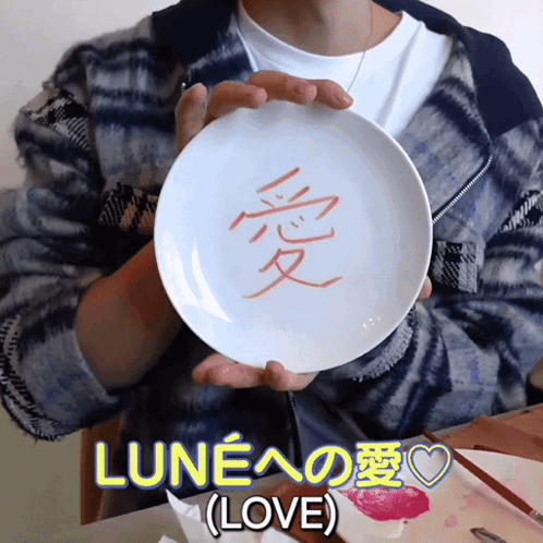 A Person Is Holding A White Plate With Chinese Characters On It GIF