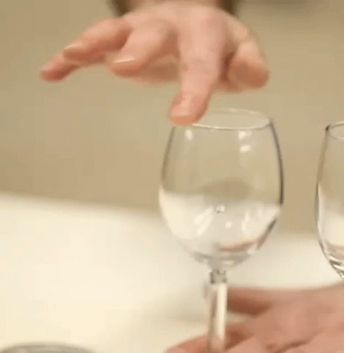 a person is holding a wine glass with their finger and a wine glass with a straw in it .