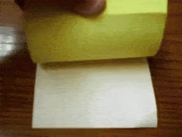 A Person Is Holding A Yellow Sticky Note And A Piece Of Paper GIF