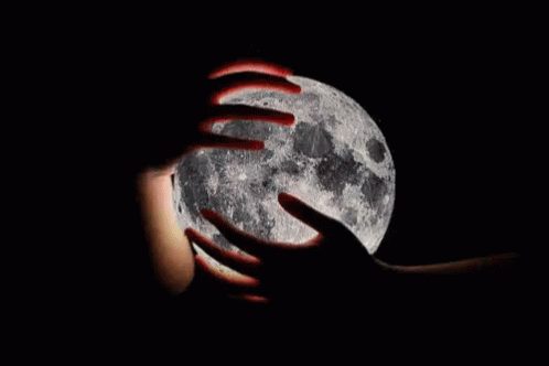A Person Is Holding The Full Moon In Their Hands In The Dark . GIF
