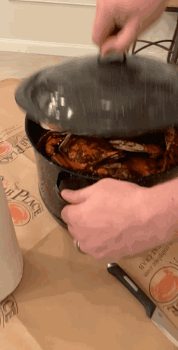 A Person Is Holding The Lid Of A Pot Of Crabs On A Table GIF