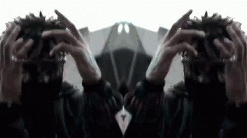 A Person Is Holding Their Hands To Their Head And Looking At A Mirror . GIF
