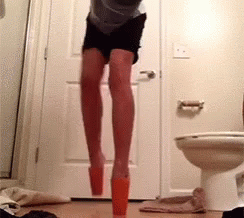 A Person Is Jumping In A Bathroom Next To A Toilet GIF