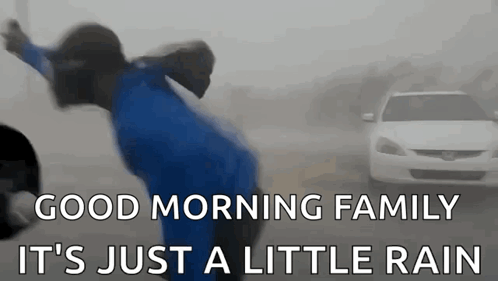 A Person Is Jumping In The Air In Front Of A Car In The Rain . GIF