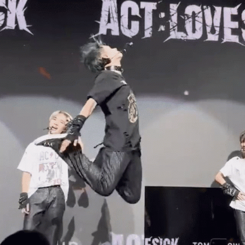 A Person Is Jumping In The Air In Front Of A Sign That Says " Act Love " GIF