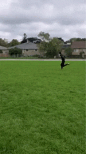 A Person Is Jumping In The Air On A Grassy Field . GIF