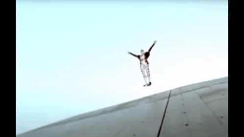A Person Is Jumping In The Air With Their Arms Outstretched .. GIF
