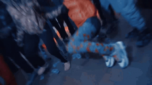 A Person Is Kneeling Down In A Crowd Of People Wearing Adidas Pants GIF