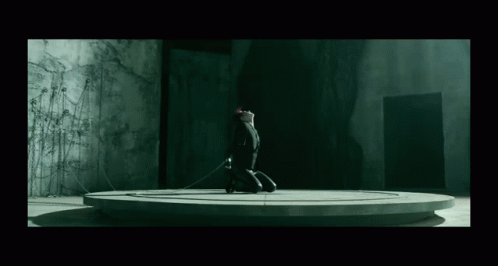 A Person Is Kneeling Down In A Dark Room With A Rope Around Their Neck GIF
