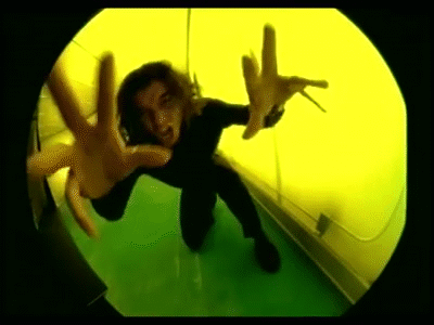 A Person Is Kneeling Down In Front Of A Yellow Wall And Making A Hand Gesture . GIF