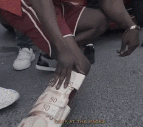 A Person Is Kneeling Down With A Stack Of Money On Their Leg GIF
