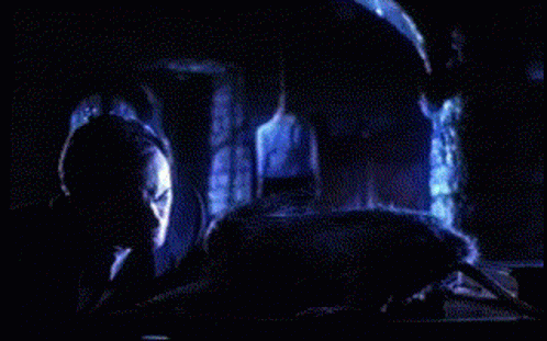 A Person Is Laying On A Bed In A Dark Room With A Blue Light Behind Them GIF