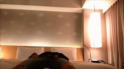 A Person Is Laying On A Bed In A Room GIF