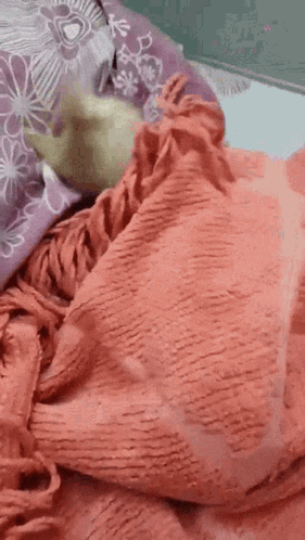 A Person Is Laying On A Bed With A Blanket And A Pillow . GIF