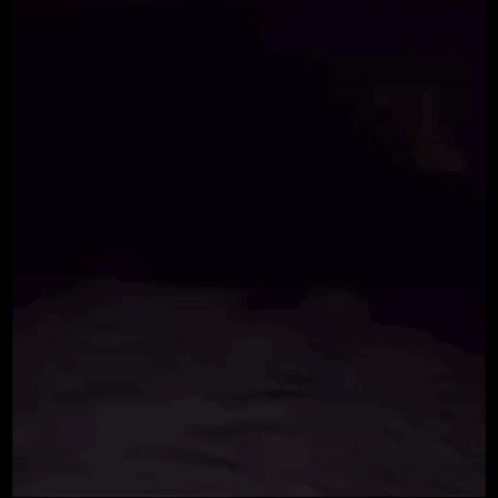 A Person Is Laying On A Bed With A Ghost Behind Them . GIF