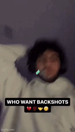 A Person Is Laying On A Bed With A Toothbrush In Their Mouth And The Words `` Who Want Backshots '' . GIF